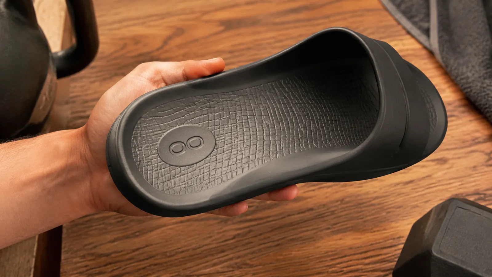 Close-up of the curved OOfoam footbed arch of a recovery slide showing the deep heel cup and arch contour