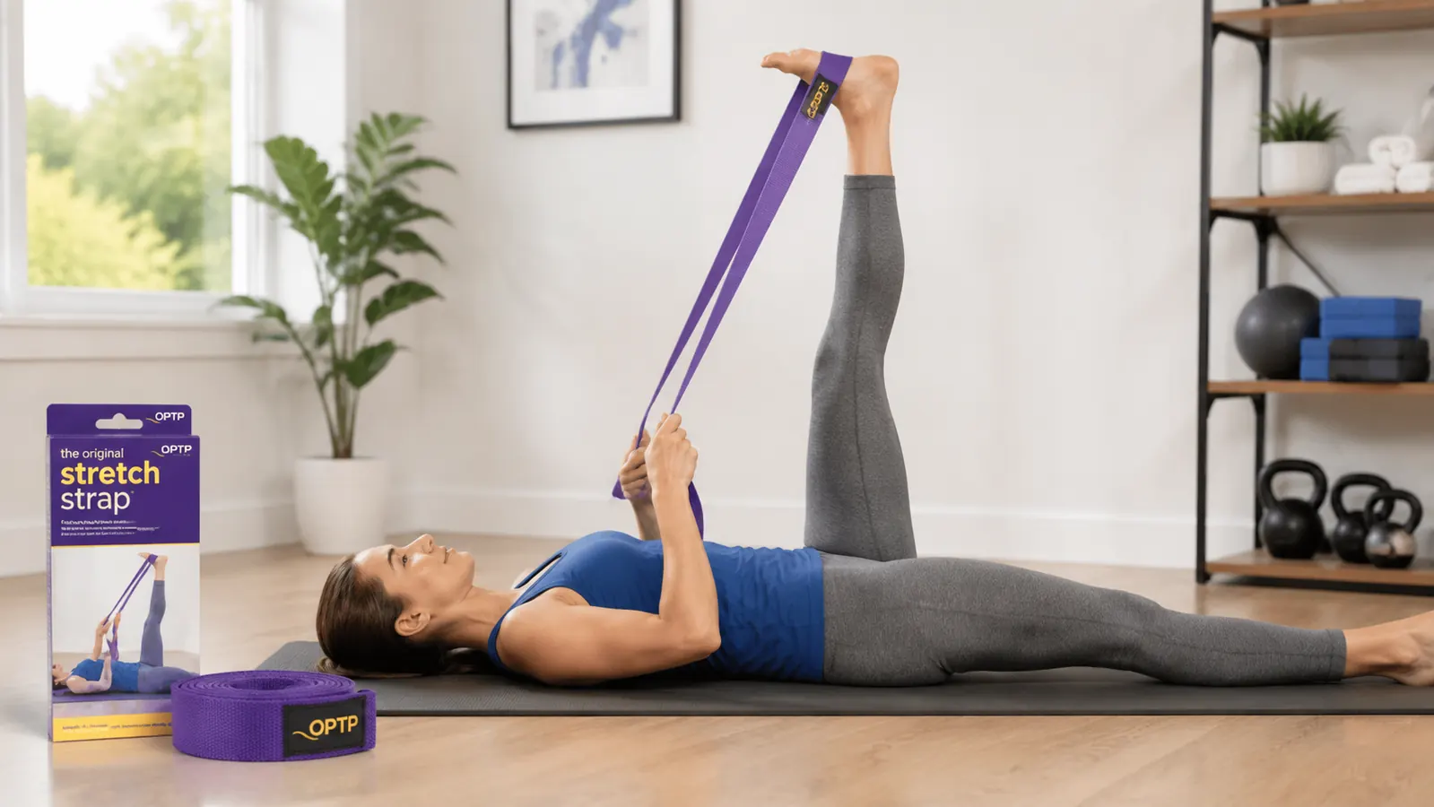 Person using a stretch strap to assist a supine hamstring stretch, lying on a yoga mat